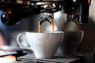 Espresso pouring from machine into white cup.