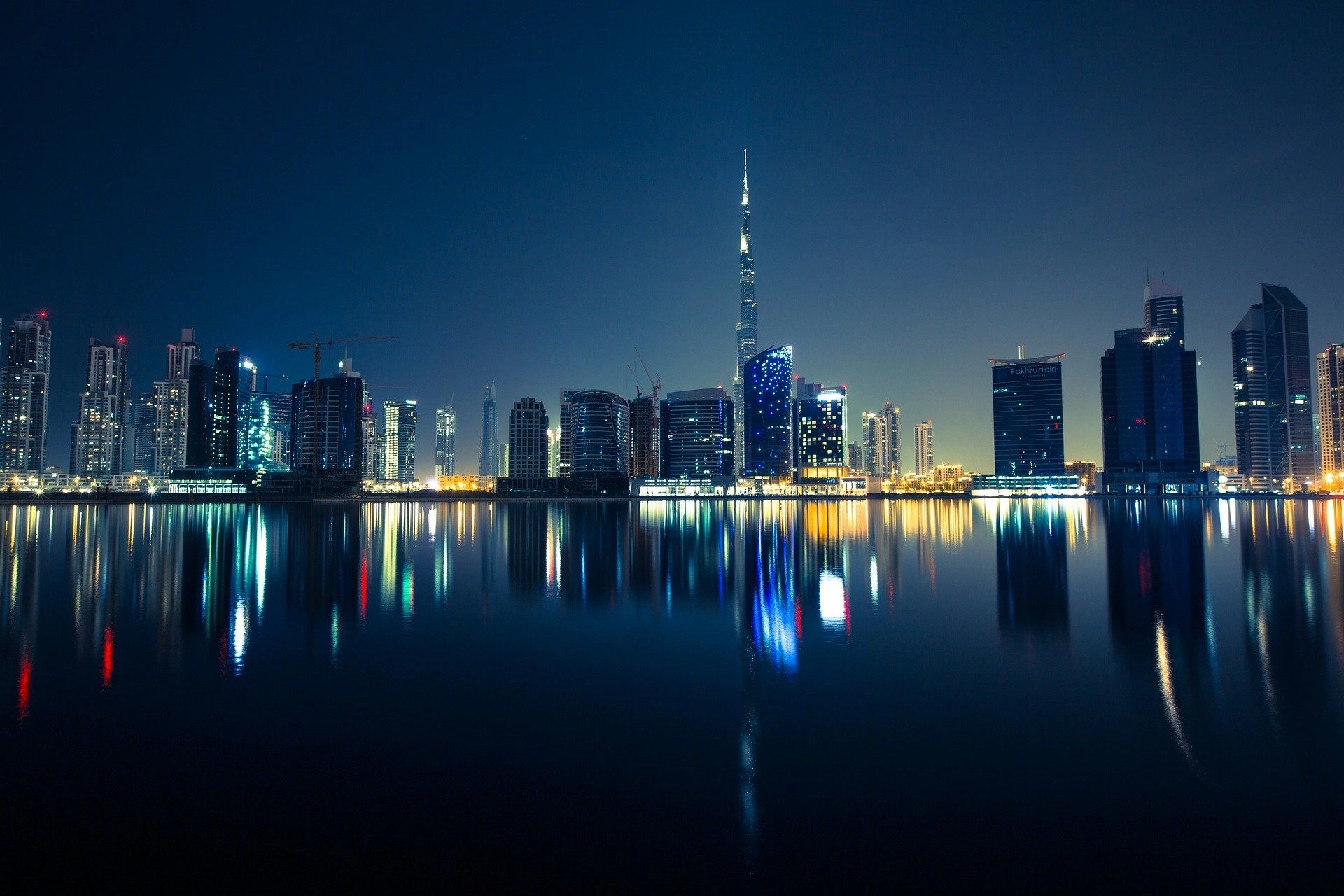 Night city skyline with reflection on water.