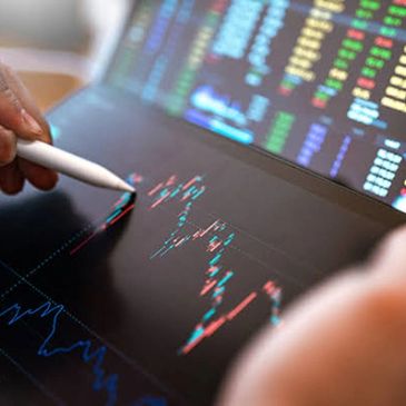 Analyst pointing at stock market charts on digital screen.