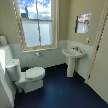 Small bathroom with toilet and sink under a window.