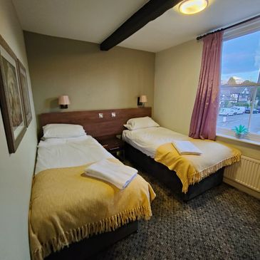 Cozy room with two single beds and yellow throws.