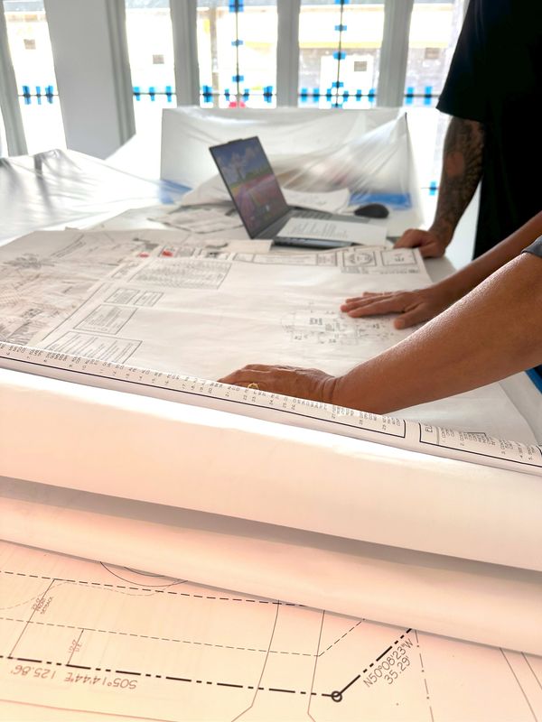 Hands reviewing architectural blueprints for a Moroney Construction shell building project