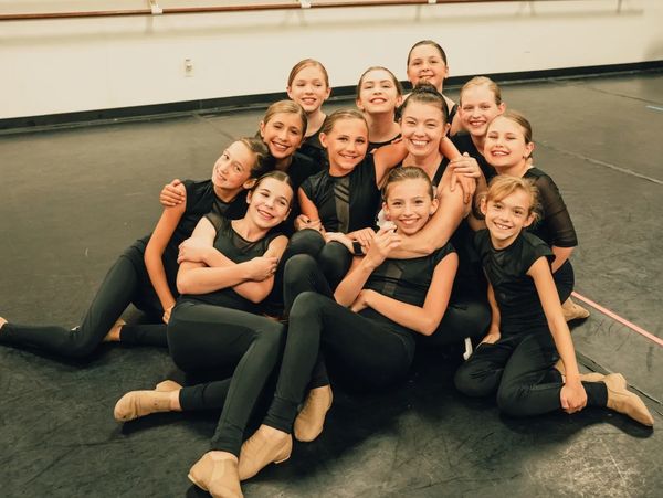 Group of young dancers posing together on a dance floor.