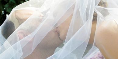 Married couple kissing under custom made bridal veil.