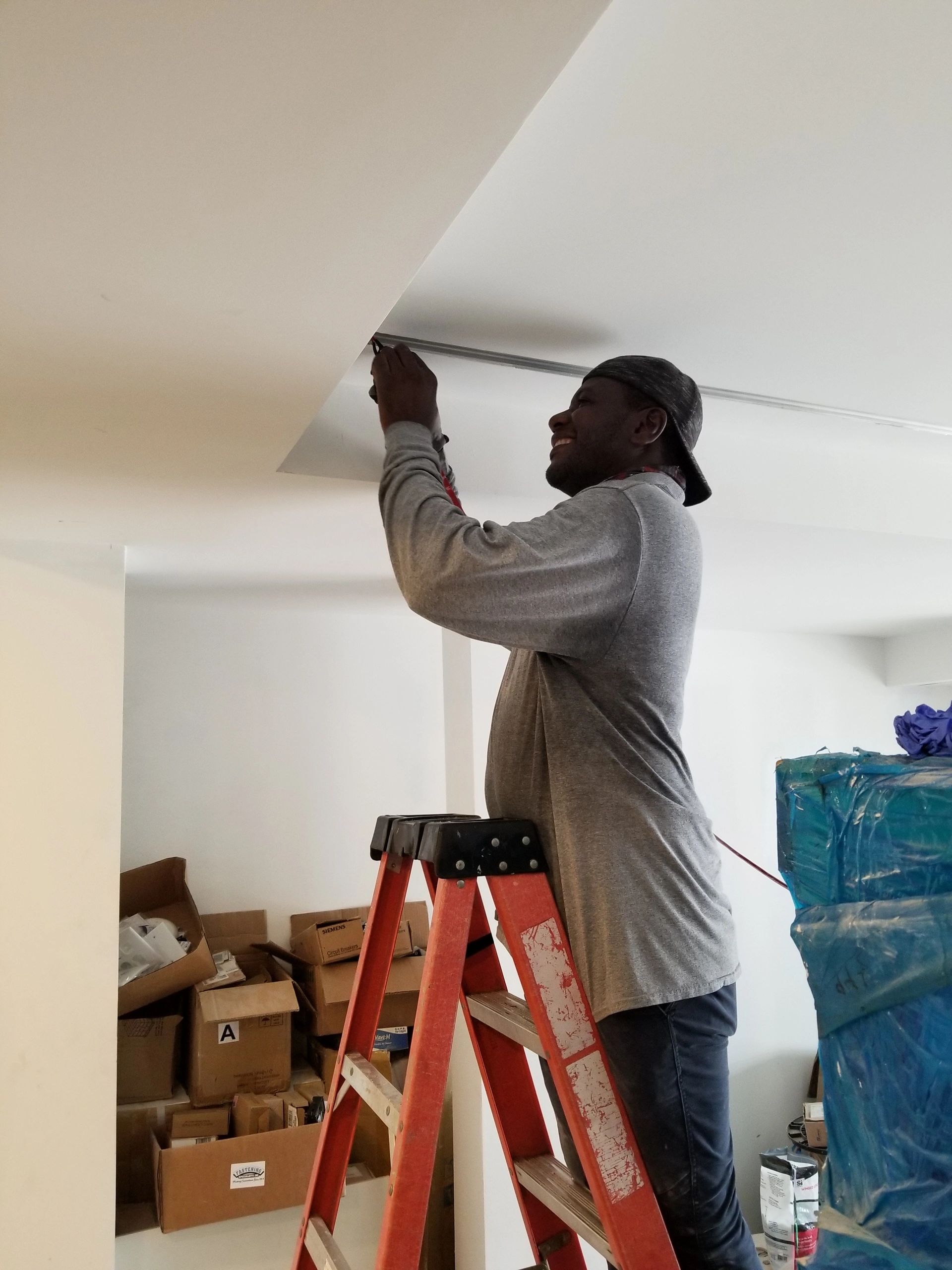 Man working on ceiling while standing on a ladder.