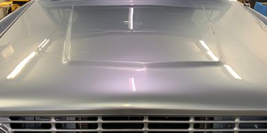 Front view of a restored classic blue Ford truck in a garage.
