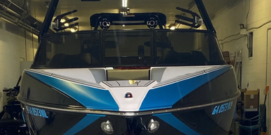 Front view of a sleek blue and black boat in a garage.