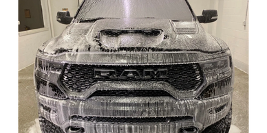 Black RAM truck covered in soap foam during a wash.