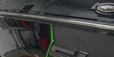 Close-up of a black boat with green tape near the 'SLX' emblem in a garage.