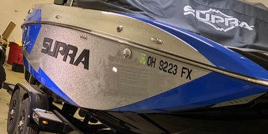 A blue and silver Supra boat on a trailer inside a garage.