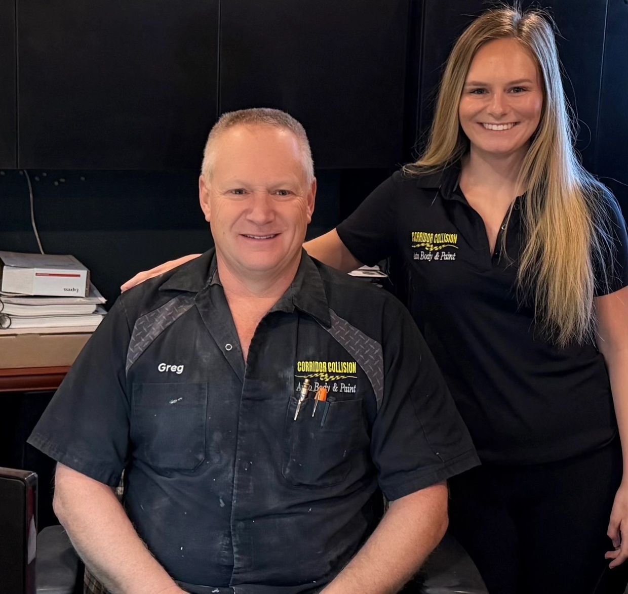 Two smiling employees from Corridor Collision in branded uniforms.