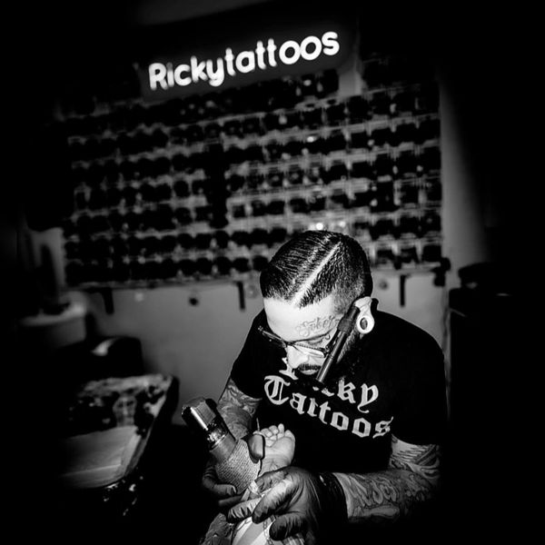 Tattoo artist working intently in a dimly lit studio.