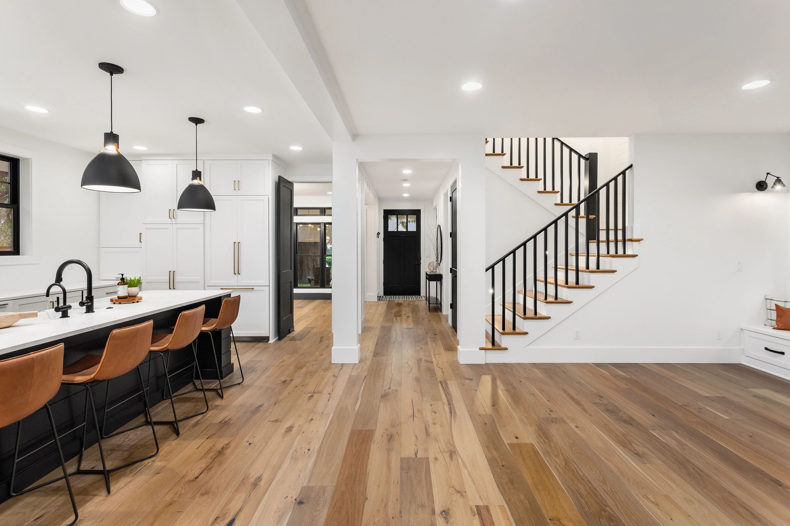 Modern open-concept kitchen and stairway featuring sleek cabinetry, pendant light