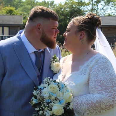 Newlyweds smiling at each other outdoors.