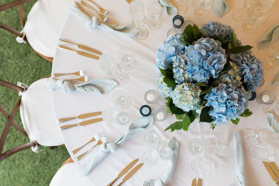 Round table decor with blue hydrangea flower arrangement at wedding reception.