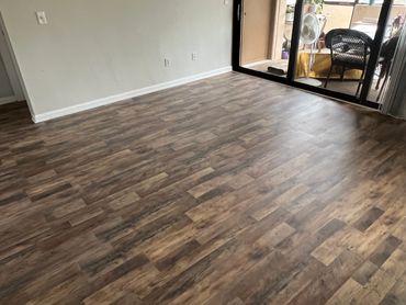 Empty room with wood-patterned flooring and sliding glass doors to a balcony.