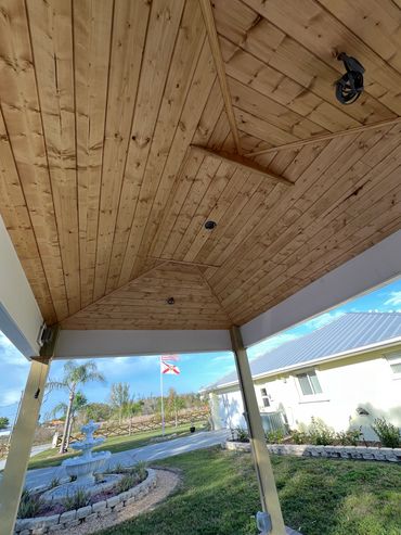 Wooden porch ceiling with a view of a garden and flags.