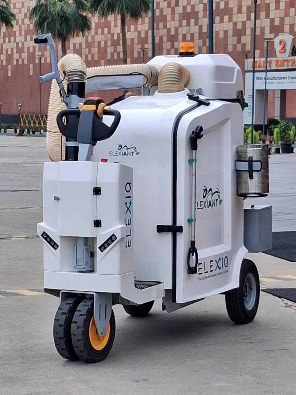 Autonomous cleaning robot with ELEXIQ branding outdoors.