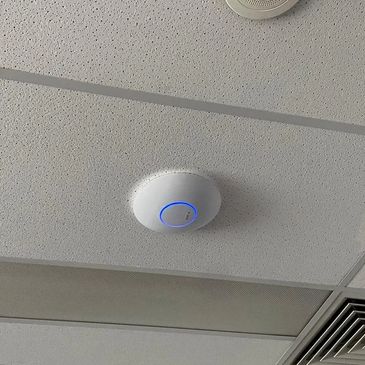 Wireless access point with a blue light on a ceiling.