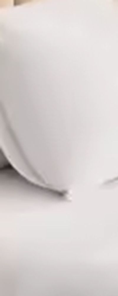Close-up of a neatly made bed with white sheets and pillow.