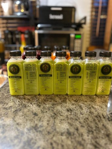 Bottles of green juice labeled 'Green Light' lined up on a kitchen counter.