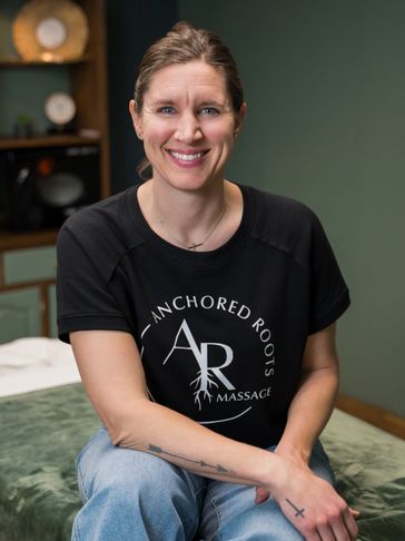 Smiling woman in casual wear sitting on a massage table.