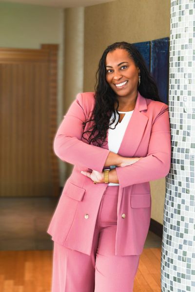 Dr. Kisha Jones, founder of KS Jones Solutions and management professor, smiling in a dusty rose sui