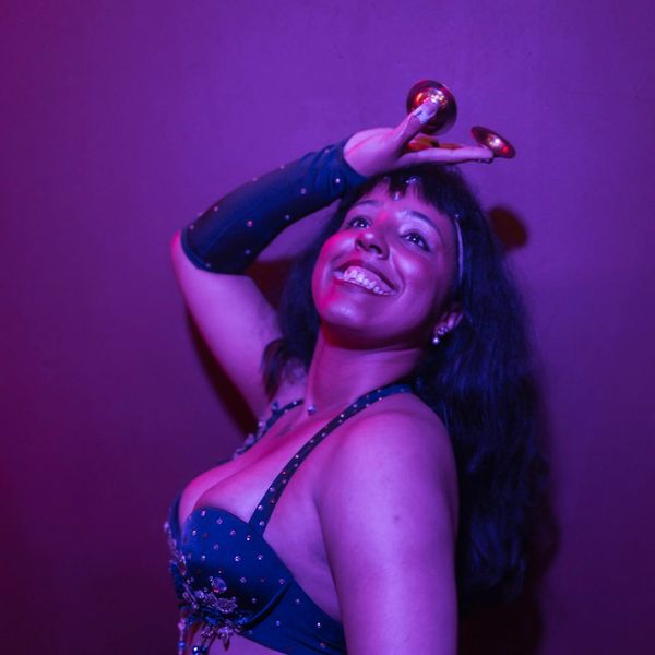 Woman dancing with finger cymbals, smiling joyfully.