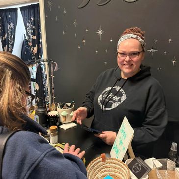 A woman in a headband and glasses helping a customer at a jewelry shop counter.