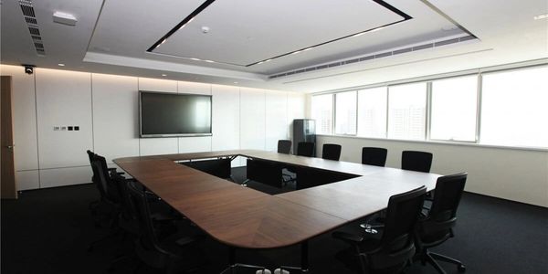 Modern, empty conference room with U-shaped wooden table and black chairs.