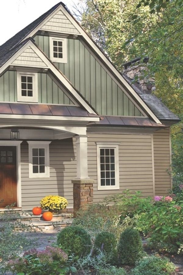 Cozy house entrance with pumpkins and fall flowers in a lush garden.