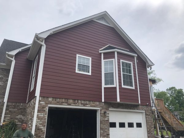 A two-story house with red siding and brick exterior on the lower level.