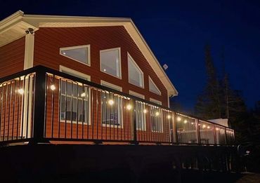 A-Frame red cabin at night with patio lanterns.