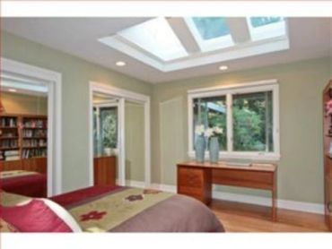 Bedroom freshly painted in a soft sage green with a skylight and dark wood furniture - interior pain