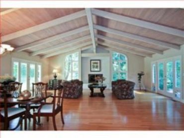Great room with vaulted wood beam ceiling, large windows, fireplace, and freshly painted trim - inte