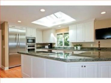Kitchen with freshly painted white cabinets, granite countertops, stainless steel appliances and a s