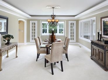 Formal dining room with freshly painted tan walls, tray ceiling, chandelier, and dark wood table and