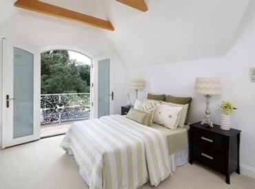 Bedroom freshly painted in soft off-white with French doors opening to a private balcony - interior
