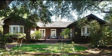Craftsman-style home exterior with dark brown wood siding and trim, surrounded by mature trees and a
