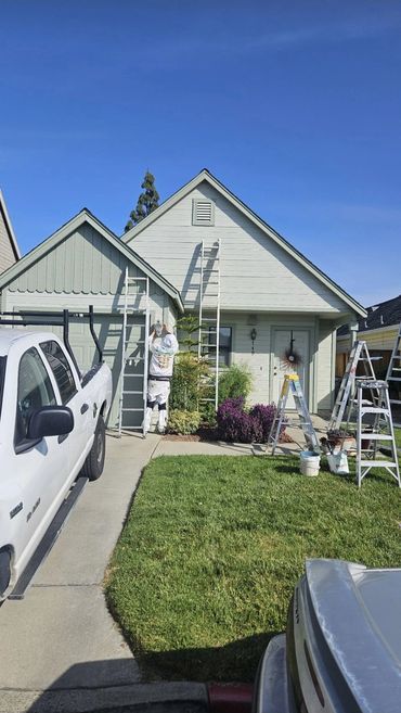 Craftsman home exterior painting with ladders and work truck on site in San Jose