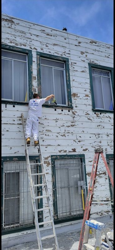 A&R Bentley painter on a ladder painting a brick building exterior, San Jose, CA (Bay Area)