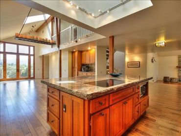 Open-concept great room with vaulted wood beam ceiling, skylight, and a wood kitchen island - interi