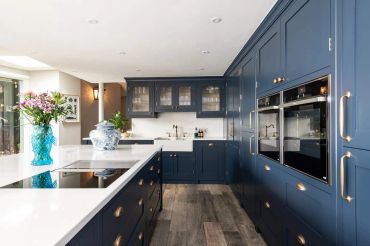 Kitchen with navy blue painted cabinets, white quartz countertops, and stainless steel appliances -