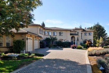 Large stucco home exterior with a freshly painted tan facade, tile roof, and paver driveway - exteri