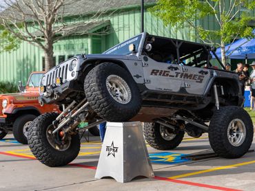 Lifted Jeep Wrangler demonstrating suspension flex at an outdoor event.