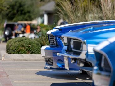 Close-up of two blue classic cars parked side by side on a sunny day.