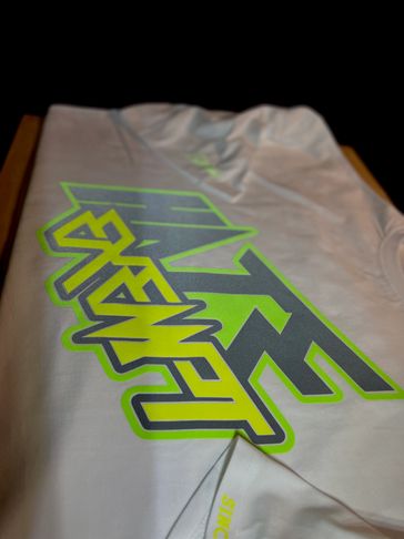 Close-up of a white shirt with bold green and gray graphic text.