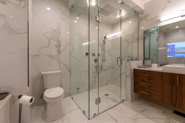 Modern bathroom with glass shower and marble walls.