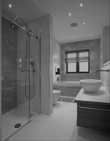 Modern bathroom with glass shower, floating vanity, and bathtub under window.