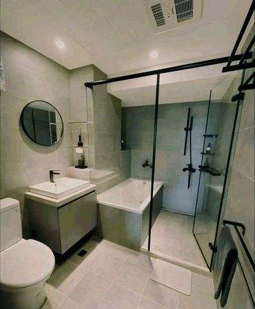 Modern grey bathroom with bathtub and glass shower enclosure.